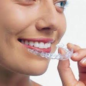 patient smiling while holding her SureSmile clear aligners