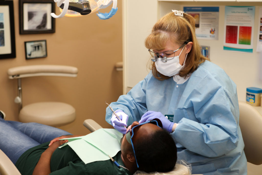 hygienist working on a patient's teeth during his emergency dentist appointment at Ridgeview Dental